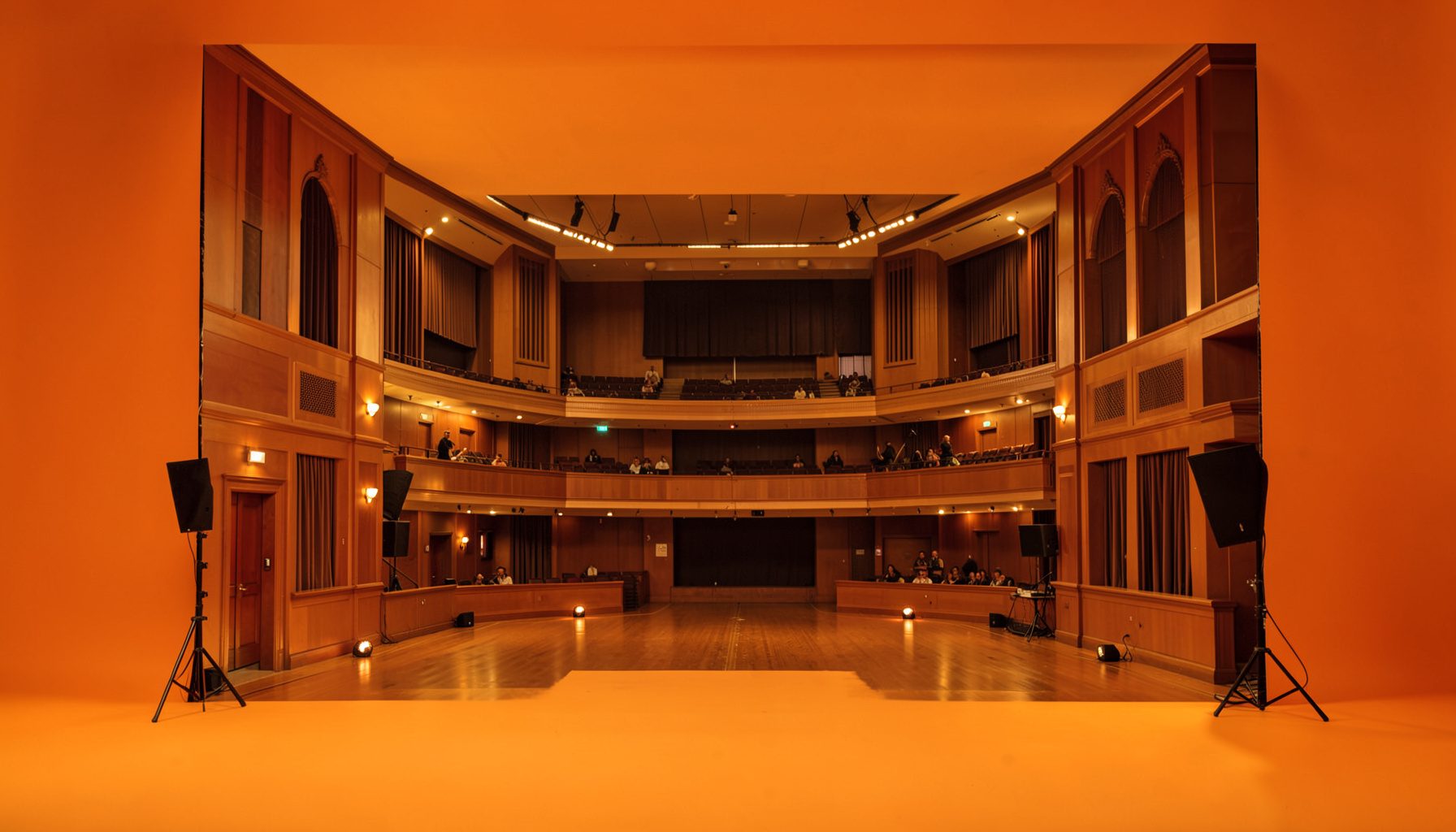 A warm atmospheric photograph of a concert hall interior with soft golden lighting