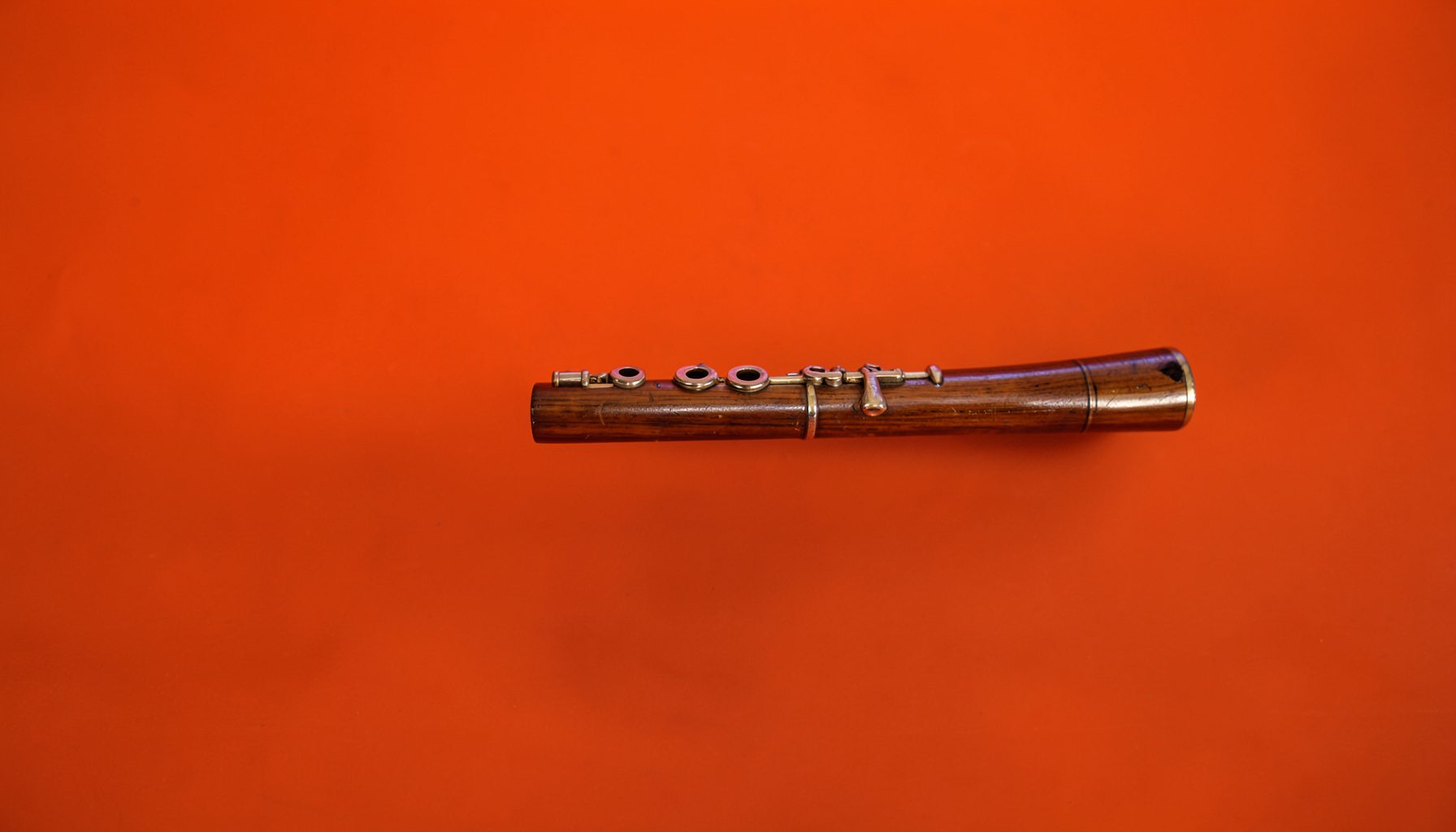 A crisp studio photograph of a vintage flute on a dark seamless backdrop, warm wood tones